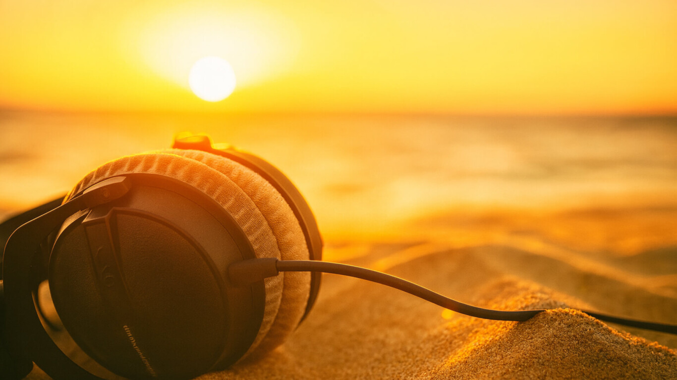 Was wird der Sommerhit 2025? Ein Kopfhörer liegt am Strand.